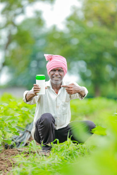 istock Indian happy farmer holding empty Bottle in hands, happy farmer showing white Bottle 1573975287