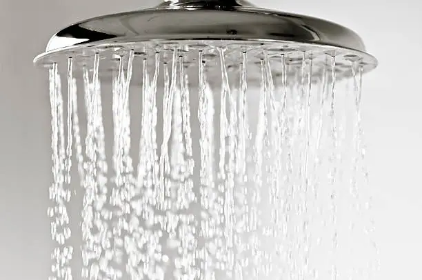 Water droplets falling from a metal shower head.