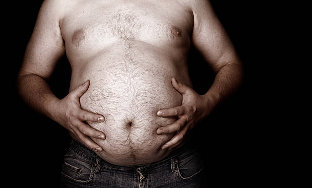 Fat man holding his stomach with jeans A fat man holds his stomach. navel stock pictures, royalty-free photos & images