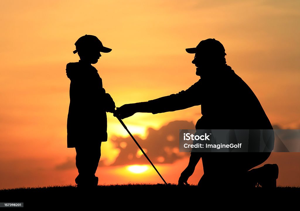 Father Giving Son Junior Golf Lesson Coaching a young boy how to golf. A professional golf instructor teaching a young boy or junior golfer how to play and hold the club. Additional themes are helping, assisting, father, son, parent, parenting, father, learning, golf academy, golf instruction, playing, sports, bonding, and relationships.  Golf Stock Photo