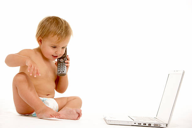 Toddler Using Phone And Laptop stock photo