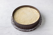 Cheesecake preparations, metal detachable baking dish with shortcrust pastry, curd filling and crumbs. Step by step, cooking stage, home baking, light gray background