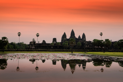 The crimson red sunset at Angkor Wat, a Unesco world heritage site at Siem Reap, Cambodia. The ancient Buddhist temple is a famous place and favorite tourist travel destination. The stone architecture in a tropical climate offers a scenic landscape and insight into Southeast Asia and East Asian culture.