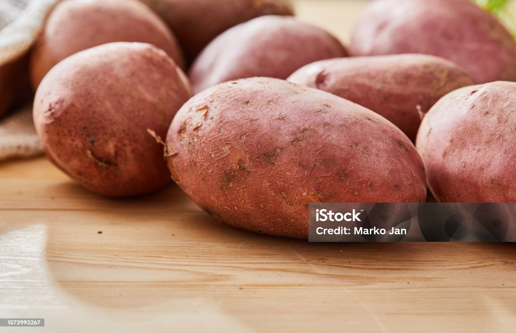 Raw red potatoes Raw red potatoes with parsley, garlic, onion, seasoning herbs and spices, ready for food preparation and baking, close up macro Sweet Potato Stock Photo