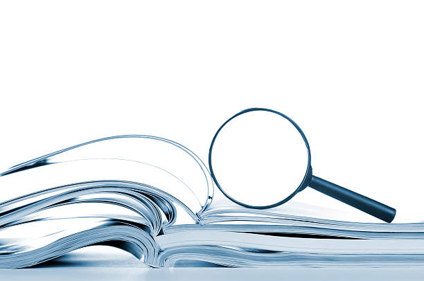 Searching, opened magazines and magnifier glass, side view, isolated white