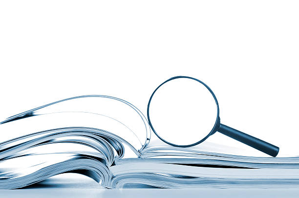 Searching, opened magazines and magnifier glass, side view, isolated white Searching... opened magazines with magnifier glass, side view, isolated on white. article photos stock pictures, royalty-free photos & images