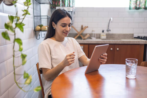 istock Caucasian woman on video call with tablet in kitchen 1573996314