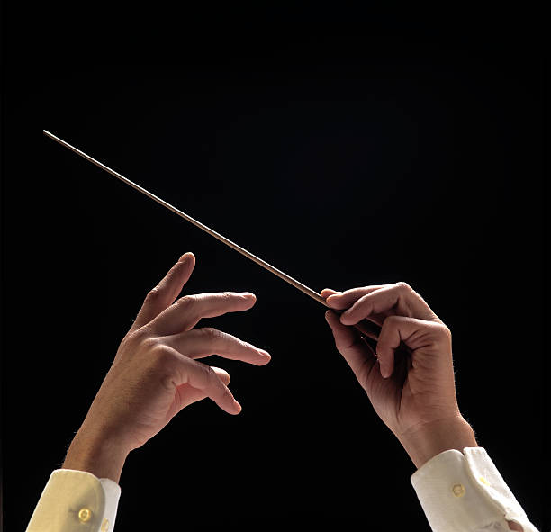 Conductors hands with baton on black background stock photo
