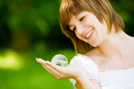 Young woman looking at a small glass globe looking for a travel destination. Good for travel issues. Shallow depth of field. Globe is in focus.