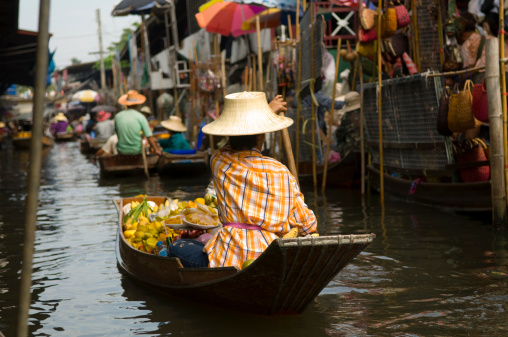 Women selling vegetables and fruit from their canoes at the Tha Kha floating market in Thailand..