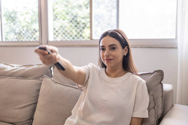 istock Woman turning on the tv by remote control 1574003827