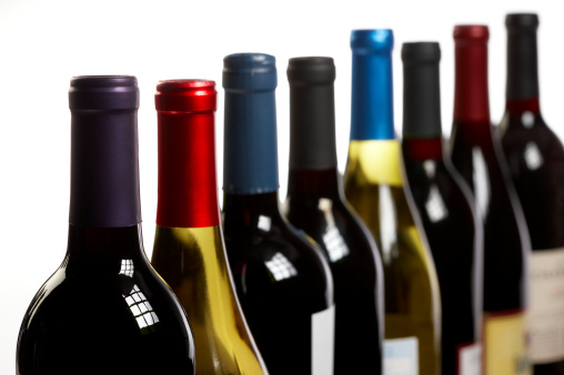 Large group of wine bottles on a white background with window light reflections. No logos or labels are showing. Shot on Canon EOS 1Ds Mark 3 with 100mm lens.