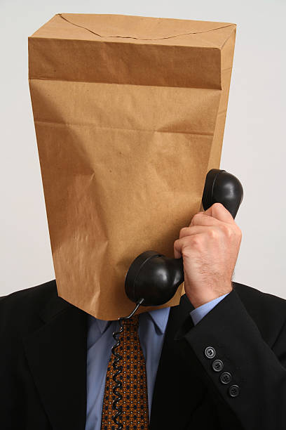 Anonymous caller Businessman with paper bag on his head making a phone call embarrassment unrecognizable person wearing a paper bag human head stock pictures, royalty-free photos & images