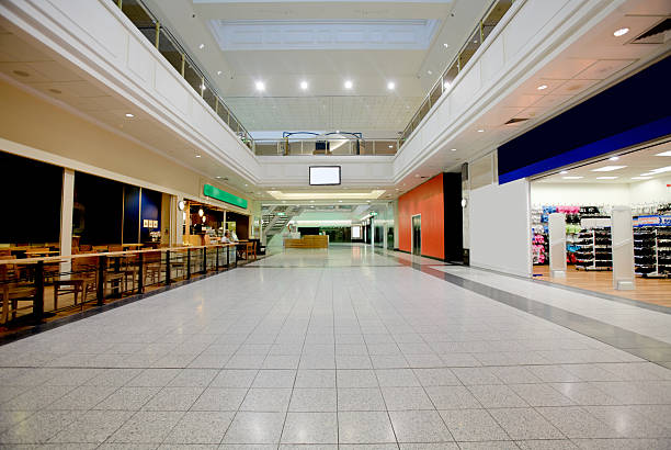 Shopping mall at rush hour, with many unrecognizable blurred people buying sales goods in various boutiques and shops.