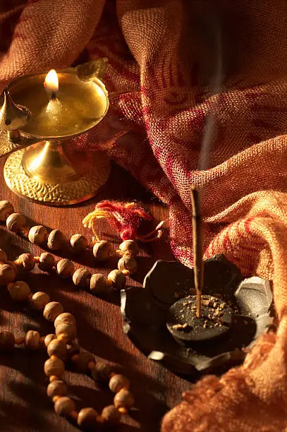 Burning incense and ghee lamp, with mala (prayer) beads lying in wait to be used for mantra repetition (japa).