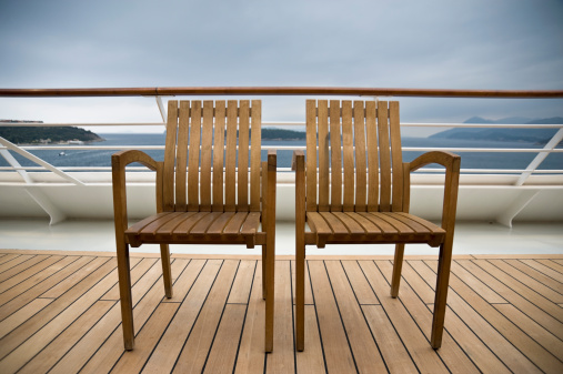 Two wooden chairs on the deck of a cruise ship with a great view