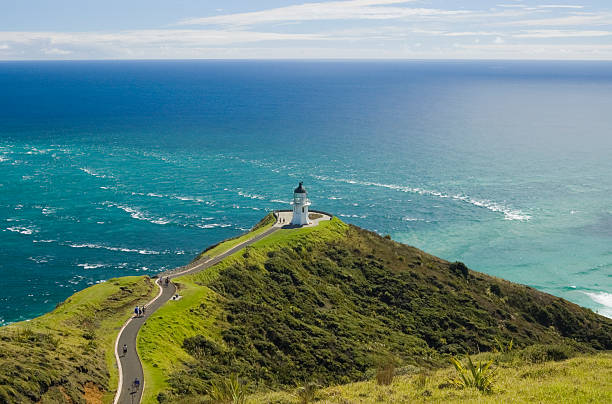 Aerial view of Cape Reinga with a stormy sea Cape Reinga, the northernmost point in New Zealand.  Featuring the Cape Reinga Lighthouse, lush mountainous terrain, and the meeting of the Tasman Sea and the Pacific Ocean. northland new zealand stock pictures, royalty-free photos & images