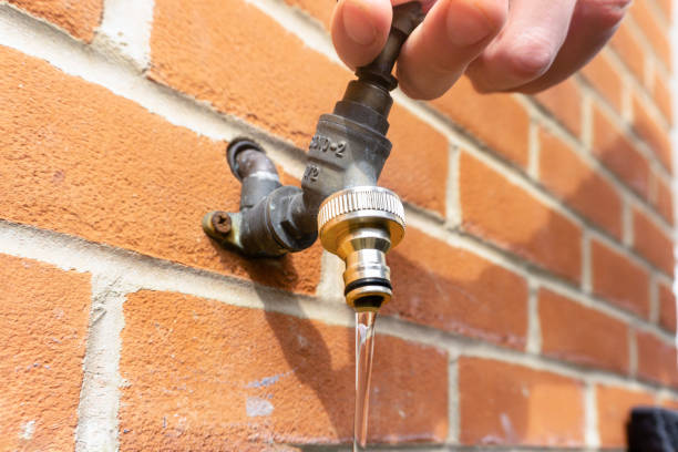 Outdoor water tap in the garden on the wall being opened and water flowing