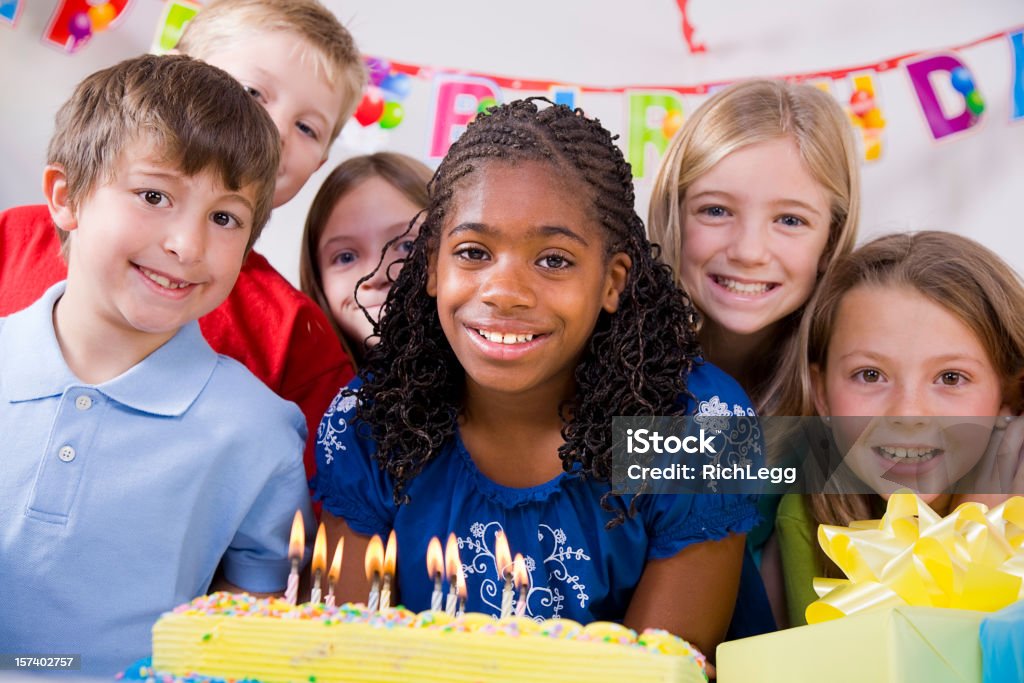 Children Blowing Out Candles on a Birthday Cake A group of children at a birthday party. African Ethnicity Stock Photo