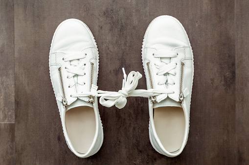 fear of commitment concept. A pair of white shoes. Tied Shoelaces Together