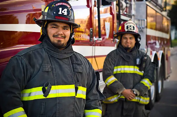 Firefighter brothers standing in front of rescue fire truck with copy-space.