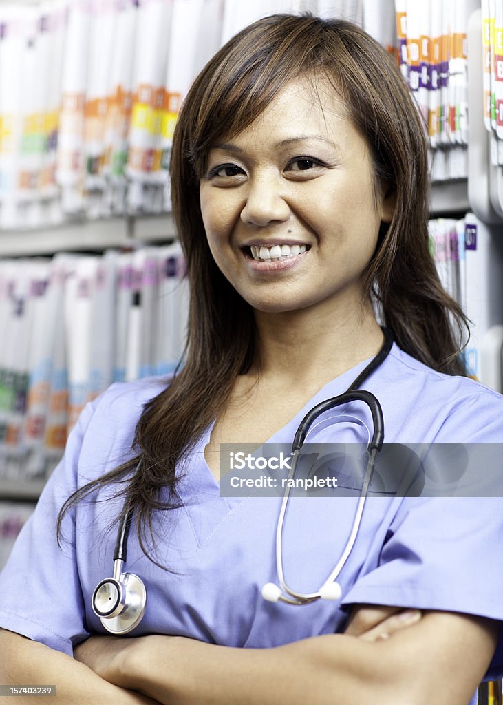 Friendly Medical Assistant A friendly female medical assistant of Asian descent standing by the medical files. 30-34 Years Stock Photo