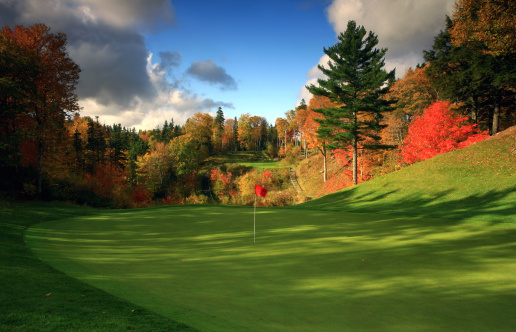 A beautiful golf course in fall. Location is Nova Scotia, Canada. A blazing red maple tree and exceptional turf conditions highlight the scene. Golf in Nova Scotia is very important industry as a number of prominent new courses have been built in the past decade. Courses are rolling and well treed and make for a relaxing and enjoyable golf experience through nature. Nobody is in this image. 