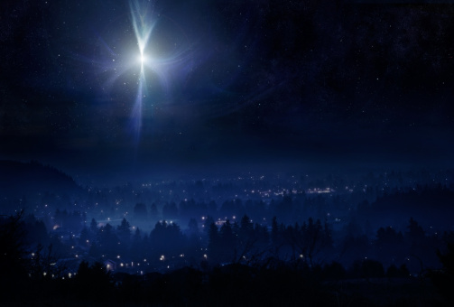 A conceptual photo montage, meant to represent the town of Bethlehem and the Christmas star in the night sky the evening that Christ was born. Horizontal with copy space.