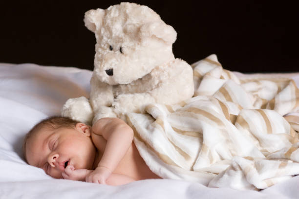 istock Newborn Baby Sleeping with Teddy Bear Stuffed Animal Watching 157403374