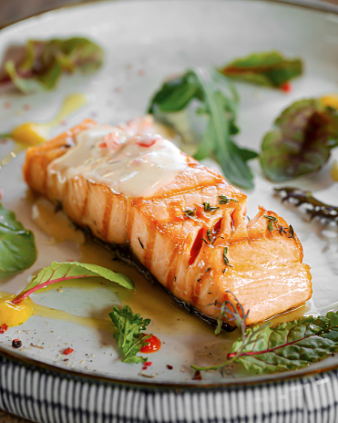 Plate of baked salmon fillet steak with lemon and herbs