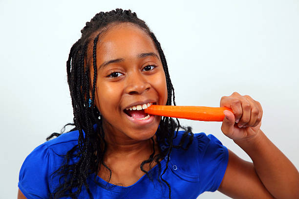 African American Girl Eating Carrot stock photo