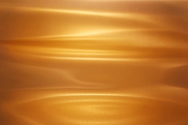 Brushed Gold Sheet of brushed gold. Lighting and reflections make it look like a pool of melted gold. All light and shadow created with lighting techniques. caramel stock pictures, royalty-free photos & images
