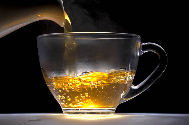 Tea pouring from a white china pot into glass cup.  oolong tea stock pictures, royalty-free photos & images
