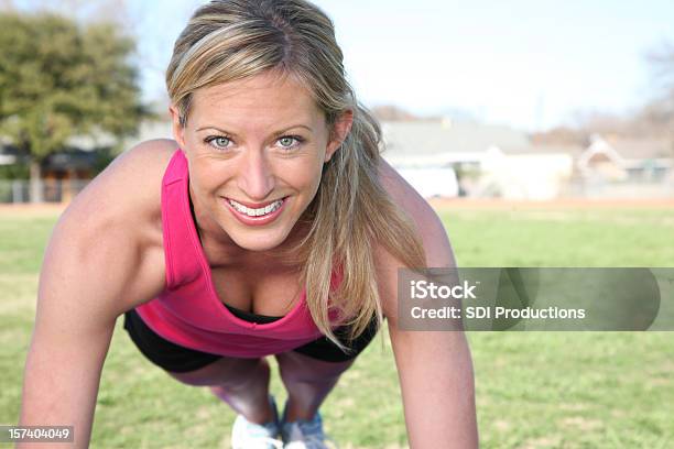 Photo libre de droit de Coupe Heureuse Femme Faisant Des Pompes Dans Un Track Field banque d'images et plus d'images libres de droit de Faire des pompes