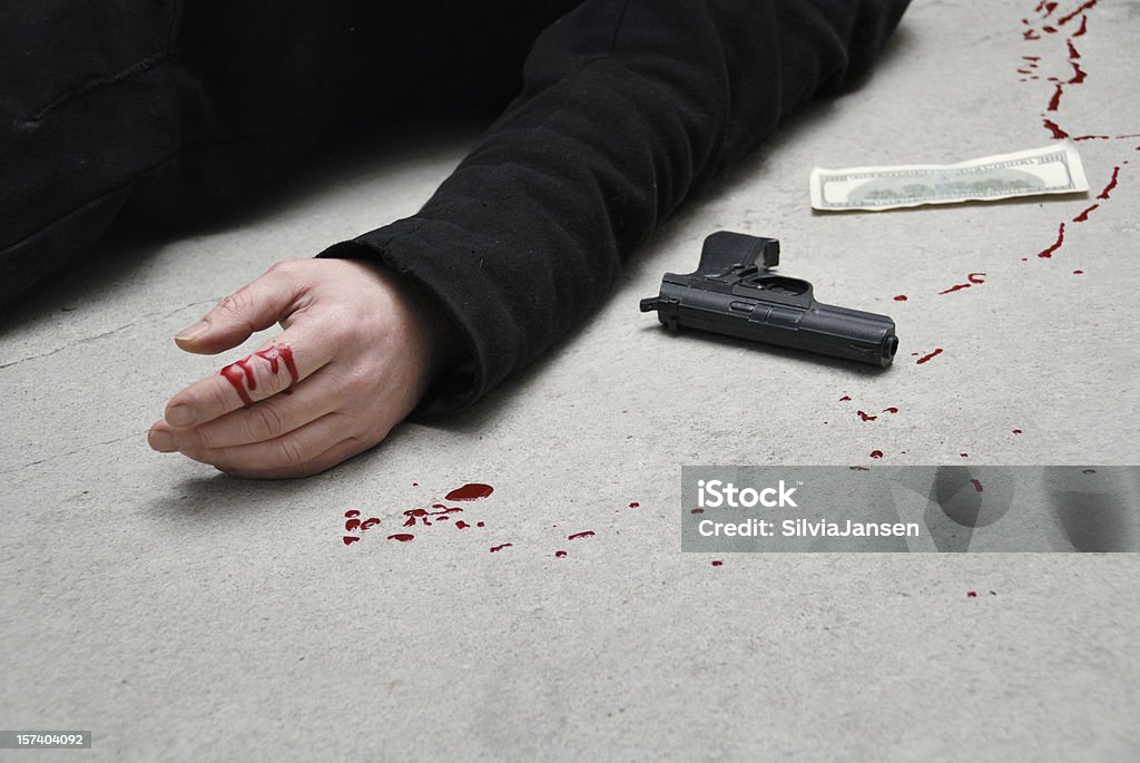 murder hand, pistol and a dollar note on a concrete ground, splashhes of blood. focus on hand. taken on the US Paper Currency Stock Photo