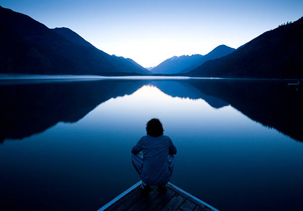 The World at Rest Person sitting quietly on the edge of a dock watching the sunset reflection stock pictures, royalty-free photos & images