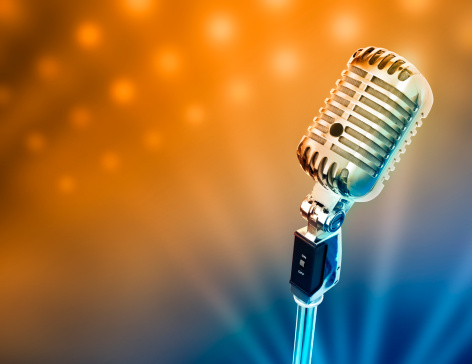 Circa 1950s microphone over stage light background.
