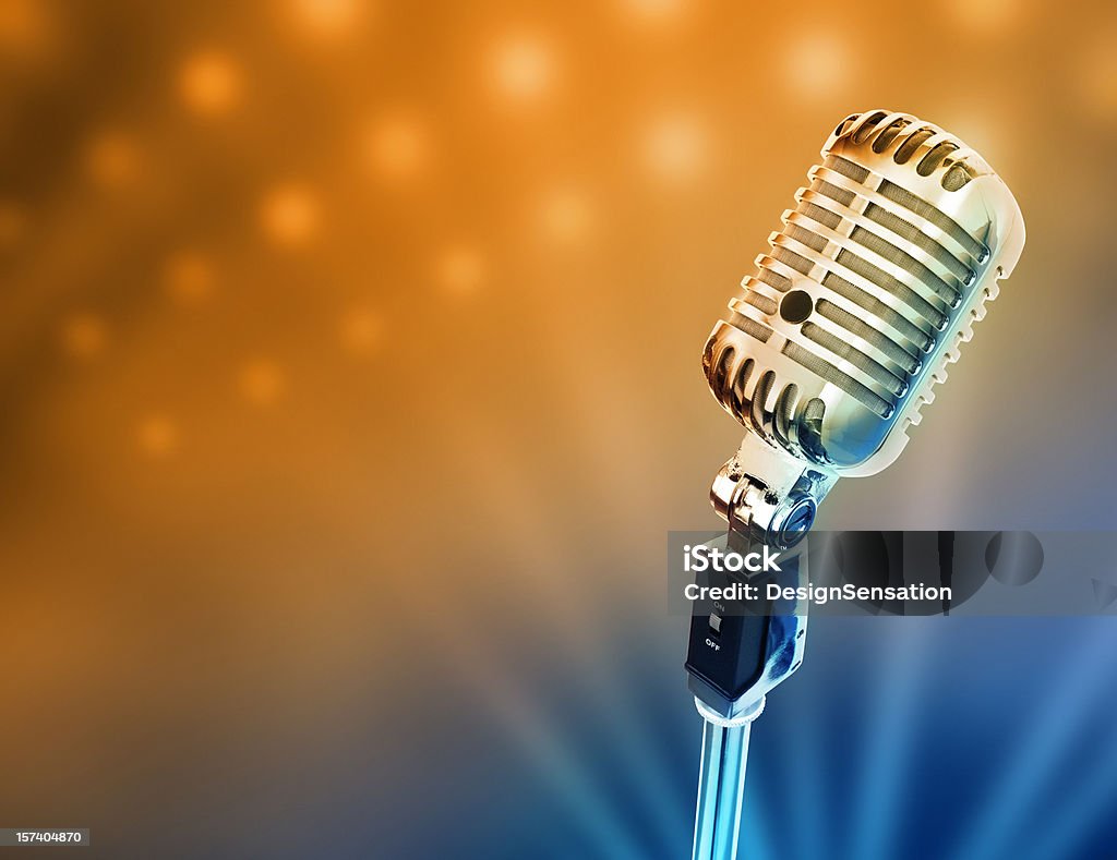 Retro microphone in front of brightly lit stage Circa 1950s microphone over stage light background. Microphone Stock Photo