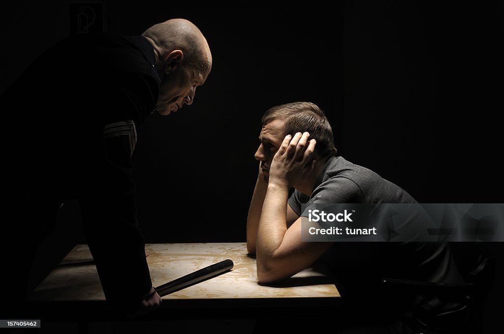 Interrogation Policeman with a criminal in interrogation room. Interrogation Stock Photo