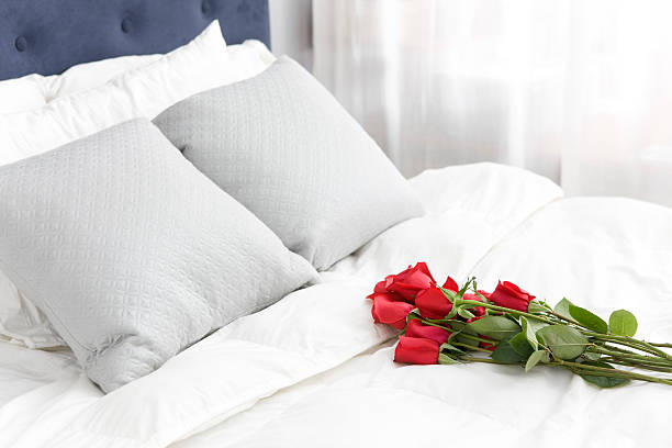 赤いバラのブーケを 1 つの白いベッドカバー、コピースペース - dozen roses rose flower arrangement red ストックフォトと画像