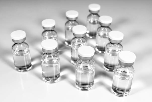 istock Glass vials with transparent liquid medication on a light background 1574081241