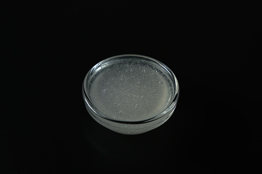 Liquid from Guar gum in glass dish on dark background. Natural thickener of Guar gum is widely used in cosmetic and food industries. Food additive E412. Stabiliser and Thickener.