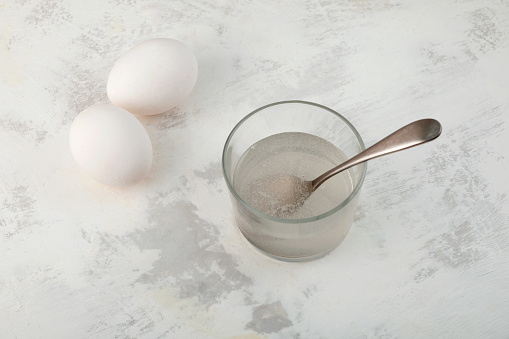 Two hen's eggs and Water soluble Xanthan gum in glass on the table. Xanthan gum used in gluten-free, lactose-free pastries as egg substitute. Food additive E415, Natural Thickener.