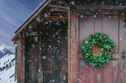 Christmas wreath n the door of a wooden cabin in the snow