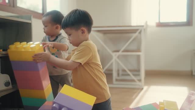 Childhood Delight: Asian Toddler Embracing Imagination and Fun While Playing with Toy Blocks Indoors.