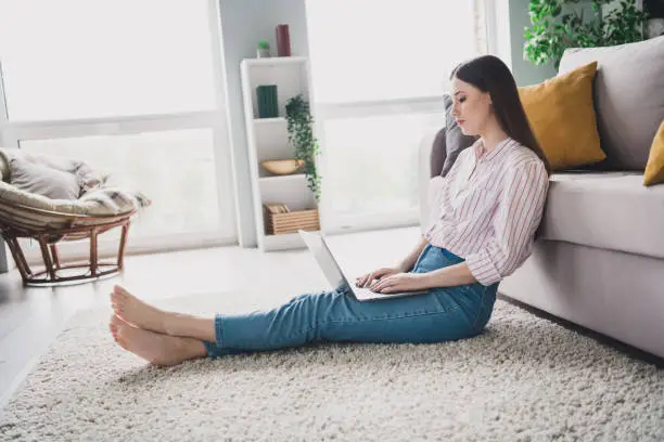 Photo of shiny sweet young girl wear striped shirt sitting floor typing apple samsung modern gadget indoors apartment room.