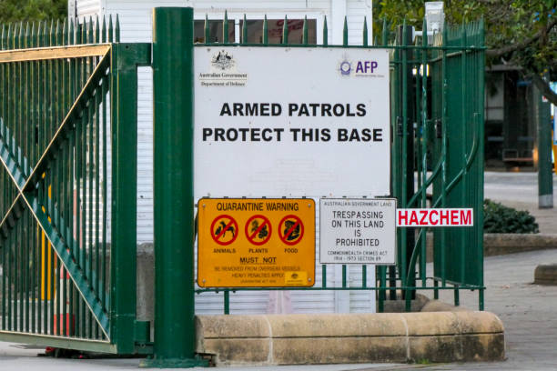 Naval Base Open Gate One of the main gates to Garden Island naval base of the Royal Australian Navy in Sydney Harbour is open on the morning after the arrival of the USS Canberra, a combat ship of the US Navy. The rising sun is reflecting on the gate. A few days later, concrete barriers were installed around this entrance. Several warning signs are attached to the fence. This image was taken at sunrise in Woolloomooloo Bay on 19 July 2023. free no sign up stock pictures, royalty-free photos & images