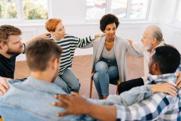 istock High-angle view of multicultural and different ages group of addicted people discuss problems and together holding shoulders each other on therapy 1574174150
