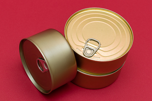 A Group of Stacked Tin Cans with Blank Edges on Red Background. Canned Food. Different Aluminum Cans for Safe and Long Term Storage of Food. Steel Sealed Food Storage Containers