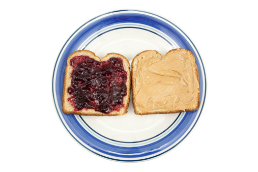 Peanut butter and jelly on wheat bread, on a plate isolated on white.